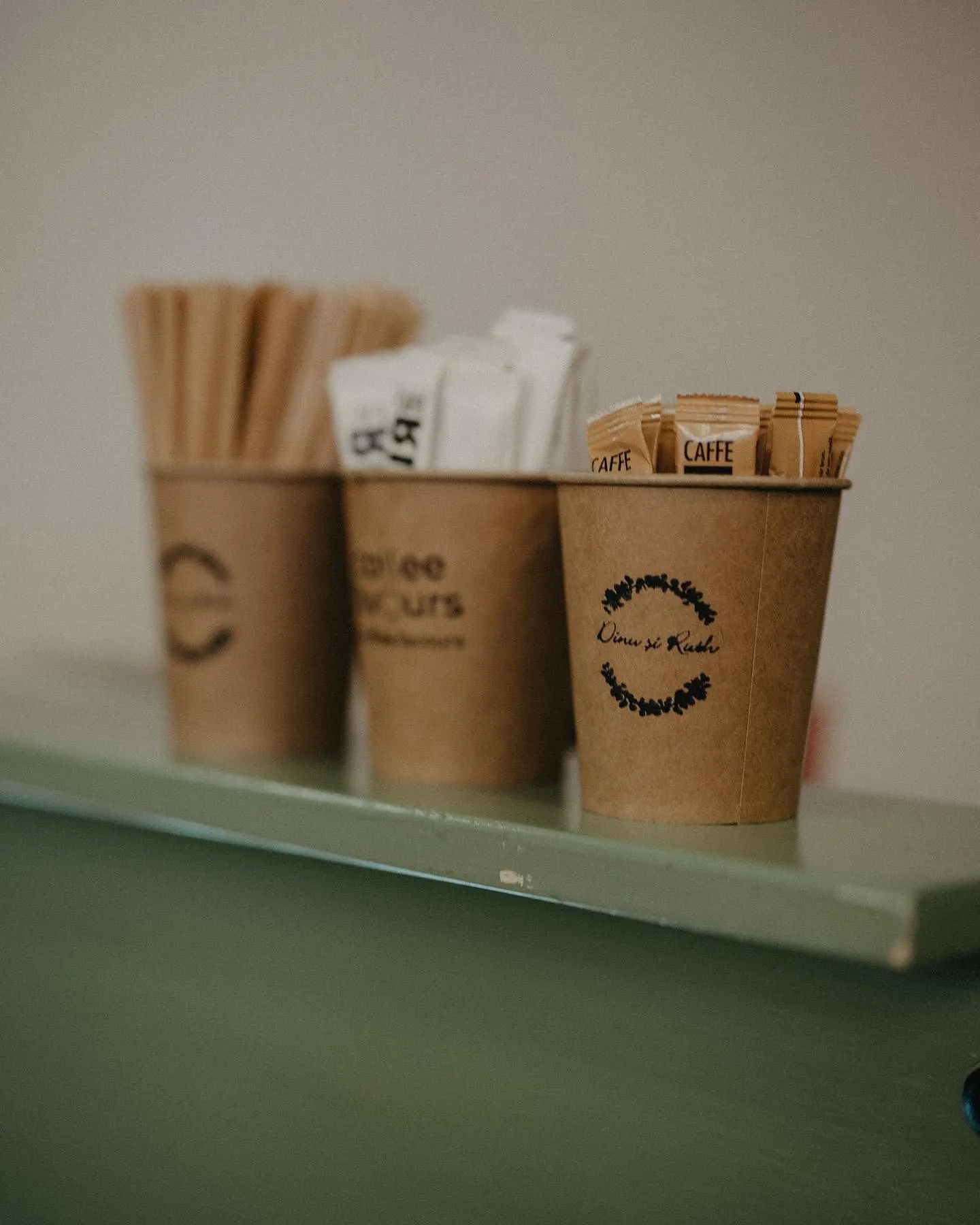Pahare kraft cu logo Coffee Favours, aliniate pe bar
